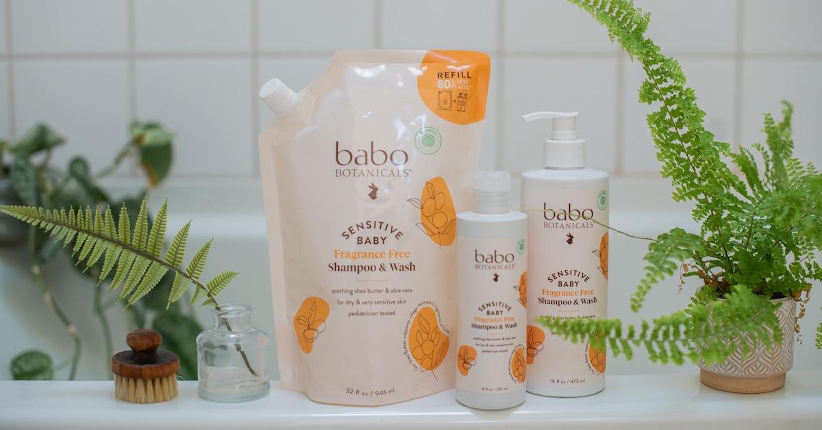 Babo Botanicals baby shampoo in three different package variations on a bathtub ledge.