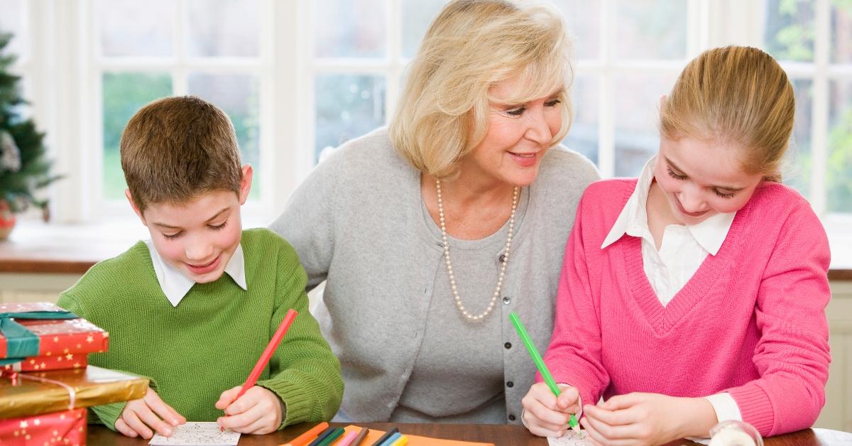 A woman and two children creating gift tags from holiday cards. 