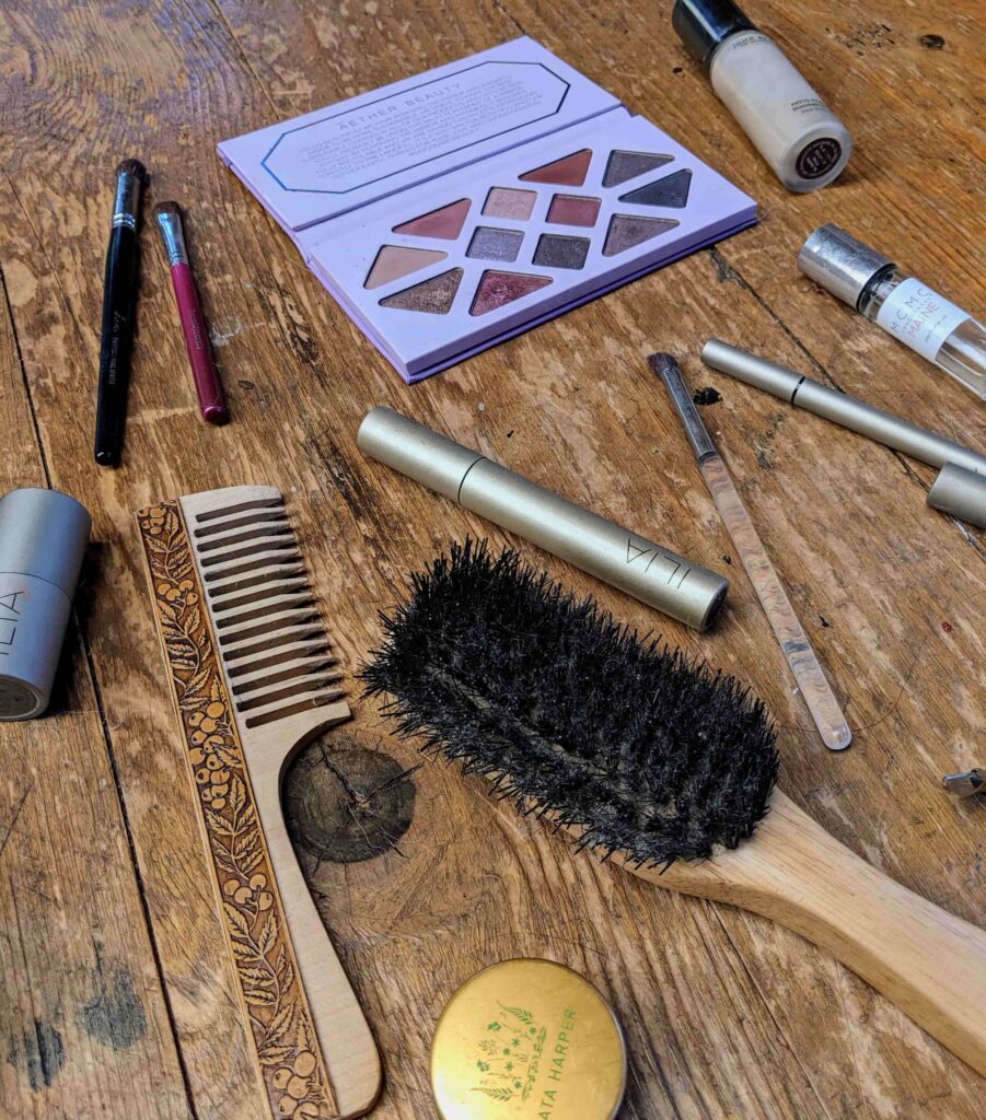 Spread out makeup capsule, along with a boar bristle brush and wooden comb.